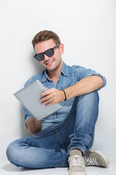 Jovem sentado no chão segurando um tablet pc — Fotografia de Stock