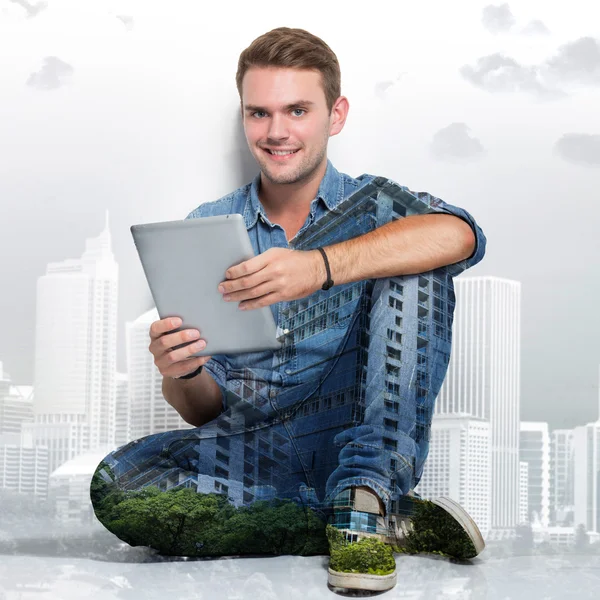 Young caucasian man sitting on the floor holding a tablet pc. mu — Stock Photo, Image