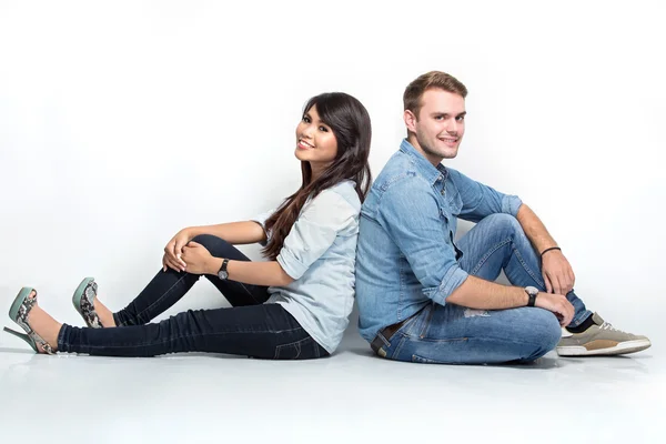 Blandade par sitter rygg mot rygg på golvet — Stockfoto