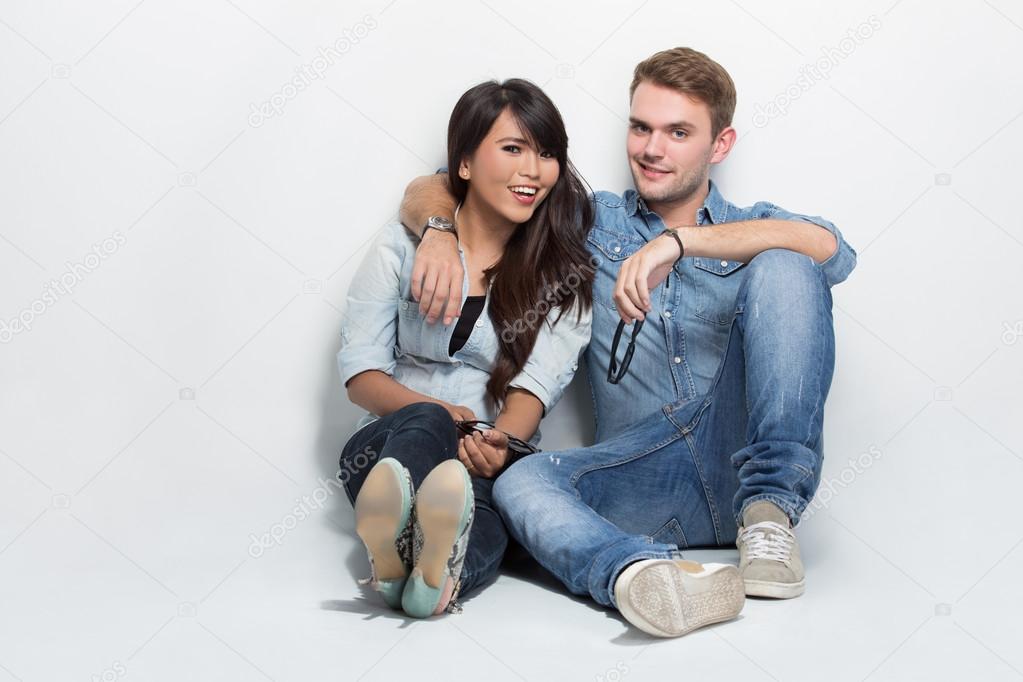 Mixed couple sitting on the floor. man embracing woman