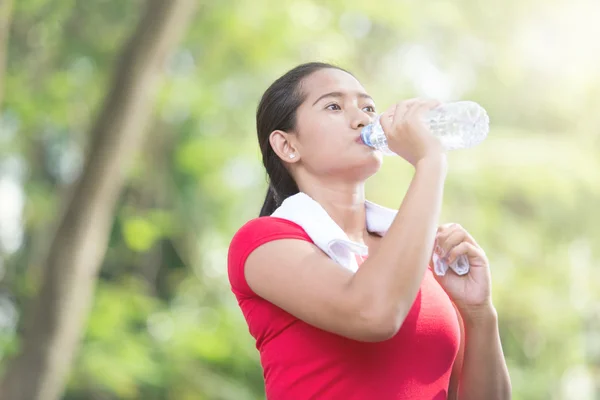 Asiatique femme boire de l'eau minérale tout en prenant pause sur l'exercice — Photo