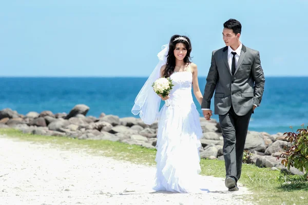 Casal recém-casado romântico de mãos dadas e caminhando na praia — Fotografia de Stock