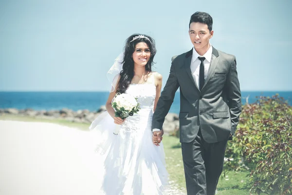 Casal recém-casado romântico de mãos dadas e caminhando na praia — Fotografia de Stock