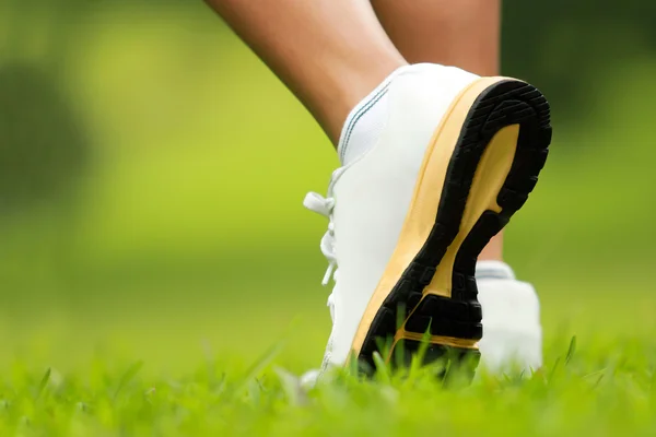 Human feet in running shoes to step on the grass — Stock Photo, Image