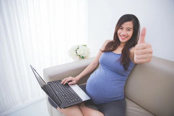 Donna incinta utilizzando il computer portatile che mostra i pollici verso l'alto — Foto Stock