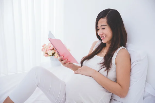 Mooie zwangere Aziatische vrouw lezen Opmerking boek, glimlachend — Stockfoto