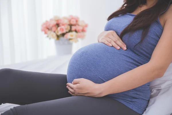 Schwangere liegt auf dem Bett, aus nächster Nähe auf dem Bauch — Stockfoto