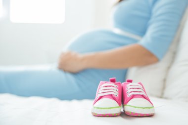 Baby Shoes with a pregnant woman on the background