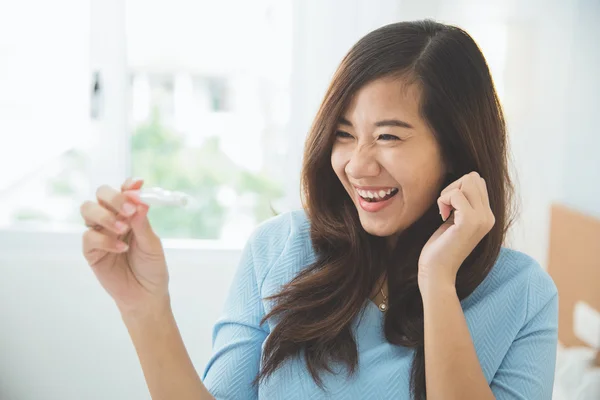 Азиатская молодая женщина с тестовым пакетом в руке, счастливо улыбается — стоковое фото