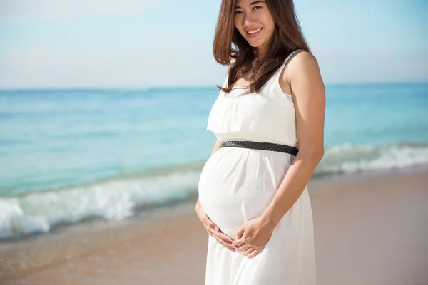 Asian pregnat woman smile into camera while touching her belly — Stock Photo, Image