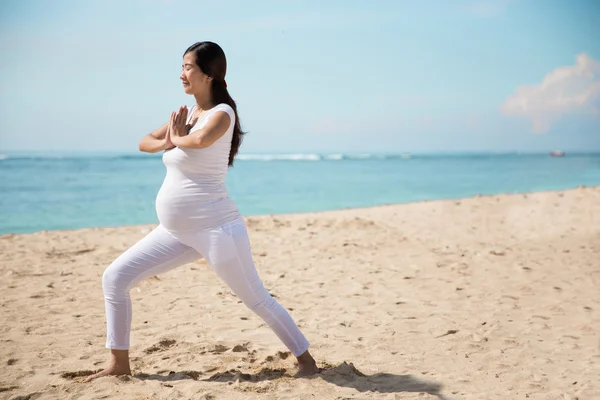 Embarazada asiática mujer haciendo yoga en el mar orilla — Foto de Stock