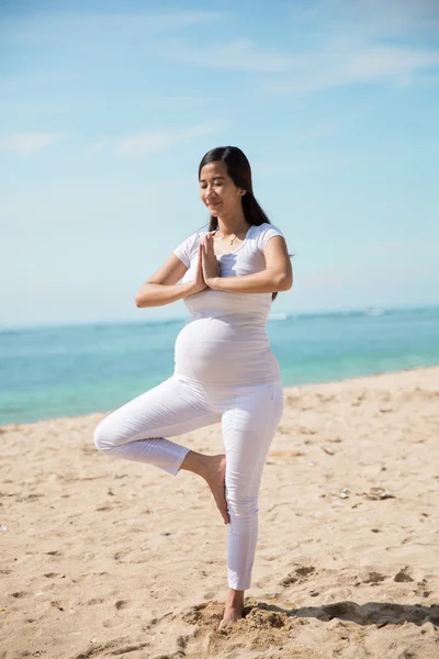 Pregnant asian woman doing yoga in the sea shore — Stock Photo, Image
