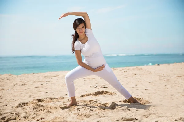 Embarazada asiática mujer haciendo yoga en el mar orilla —  Fotos de Stock