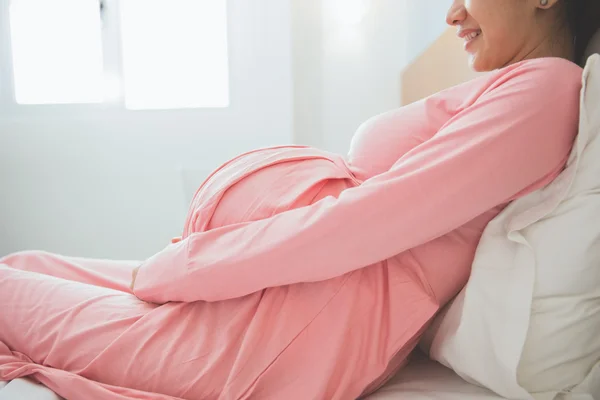 Aziatische gelukkig zwangere zittend op het bed, glimlachend — Stockfoto