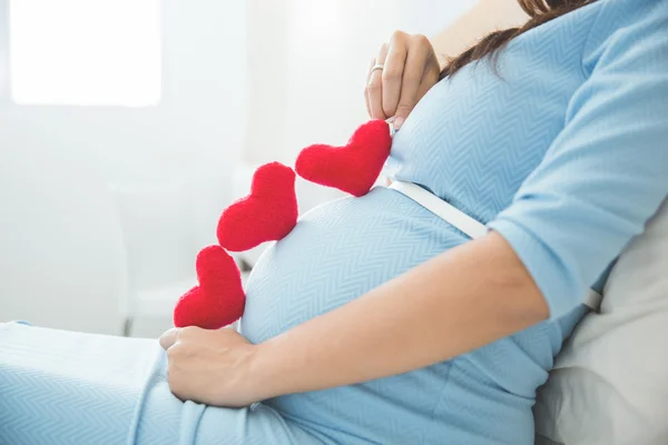 Asiática joven embarazada mujer poner corazón forma accesorios en su tu — Foto de Stock