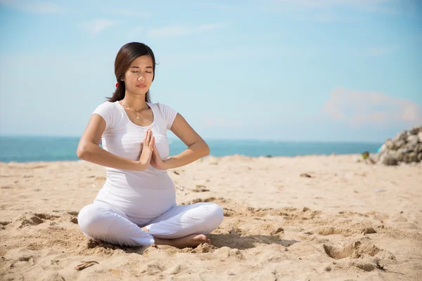 Mujer embarazada haciendo yoga en la playa — Foto de Stock