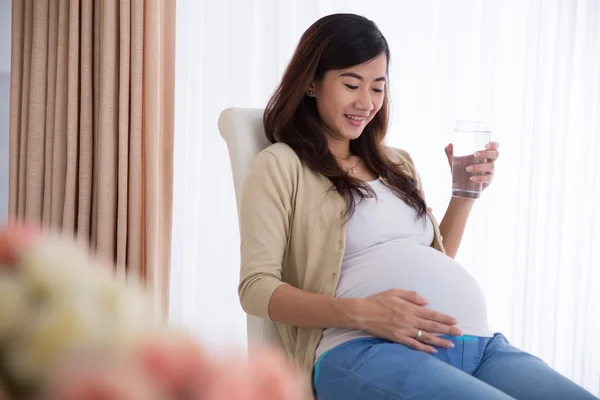 Pregnant asian woman drinking a glass of water — Stock Photo, Image