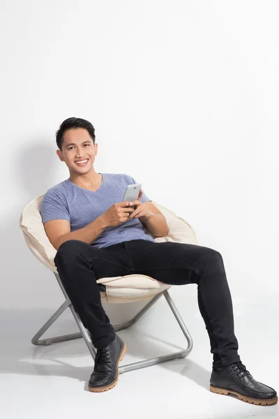 Człowiek posiadający handphone siedząc na krześle — Zdjęcie stockowe