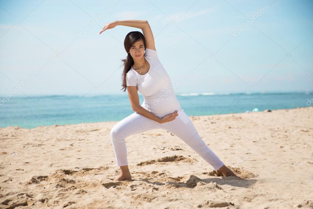 Pregnant asian woman doing yoga in the sea shore Stock Photo by