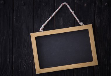 Ahşap koyu arka plan üzerinde yatay olarak asılı siyah yazı tahtası