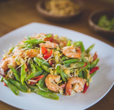 Tavada karides kare beyaz plaka üzerinde fasulye ile