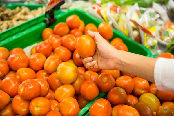 Vrouw de hand plukken van een tomaat op een markt — Stockfoto