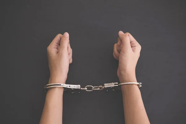 Руки с наручниками на черном фоне — стоковое фото