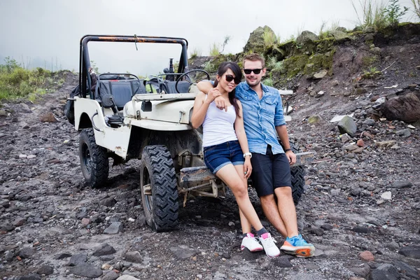 Två ung man och kvinna sitter framför ett hans jeep — Stockfoto