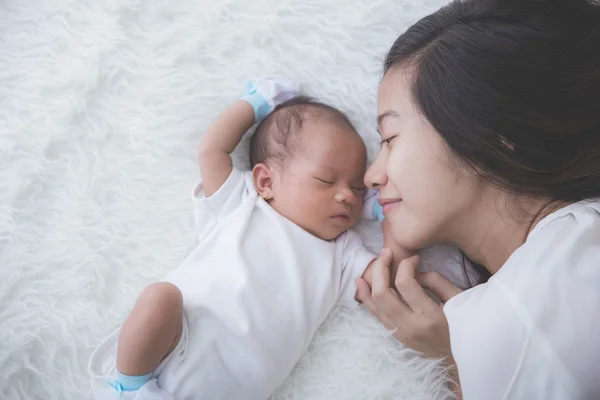 Junge Mutter legt ihr Neugeborenes schlafend auf das Bett, Nahaufnahme — Stockfoto