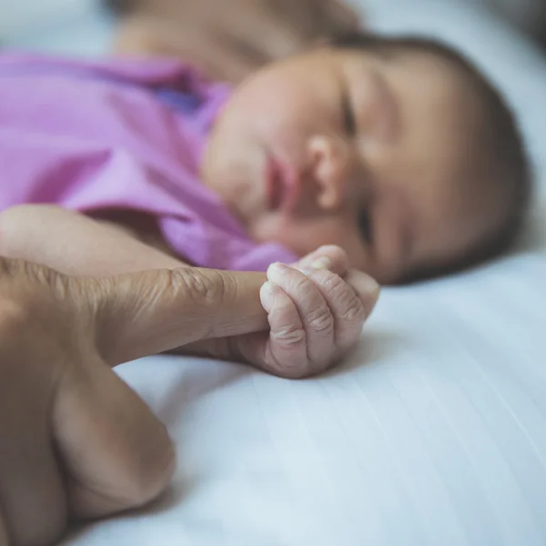 Nyfött barn uppkrupen om på en filt, hålla finger, clos — Stockfoto