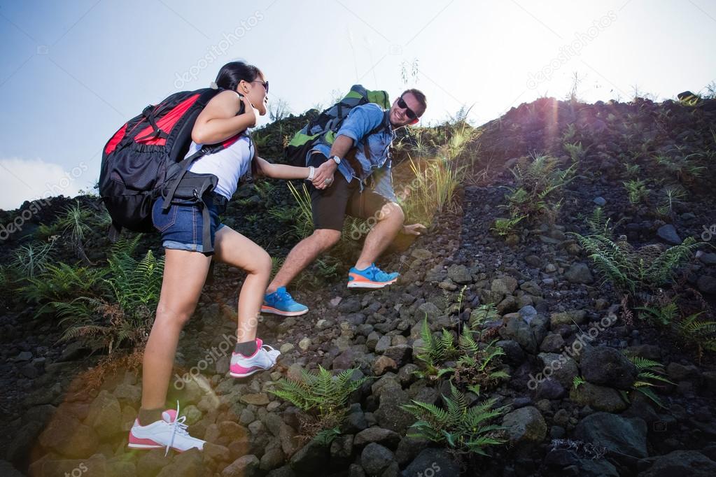 Mixed race couple go trekking together, walking on an uphill,  n