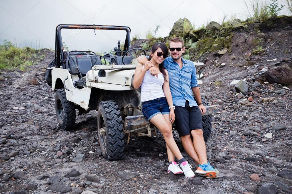 two young man and woman sitting in front of a his jeep