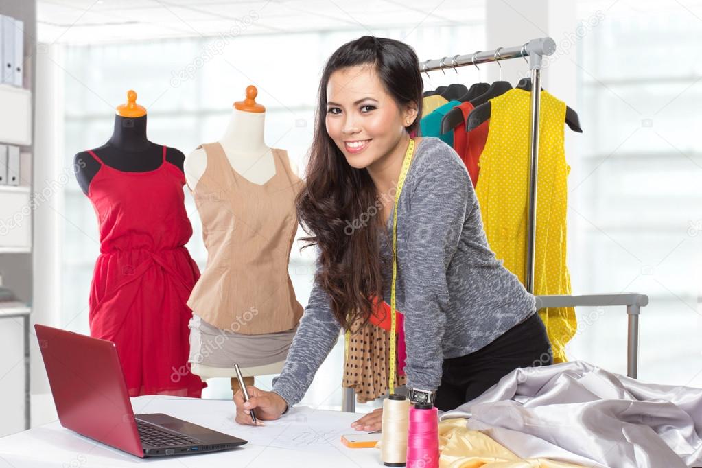 Young asian designer woman using a laptop and smiling,clothes ha