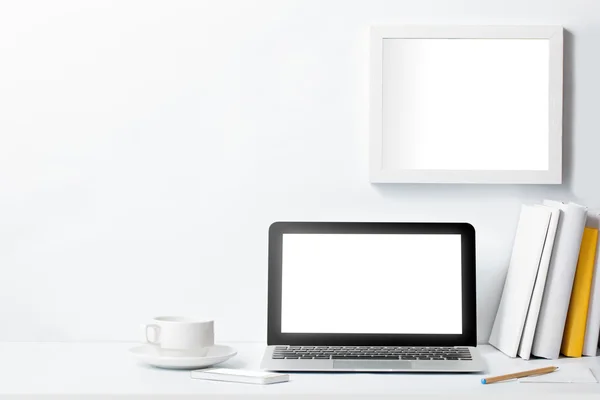 Laptop na mesa de trabalho e quadro na parede branca — Fotografia de Stock