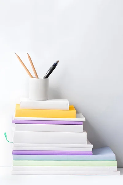 Stapel boeken en schrijfwaren in glas op witte achtergrond — Stockfoto