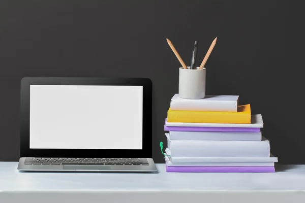 Ноутбук і стопка книг на білому столі — стокове фото