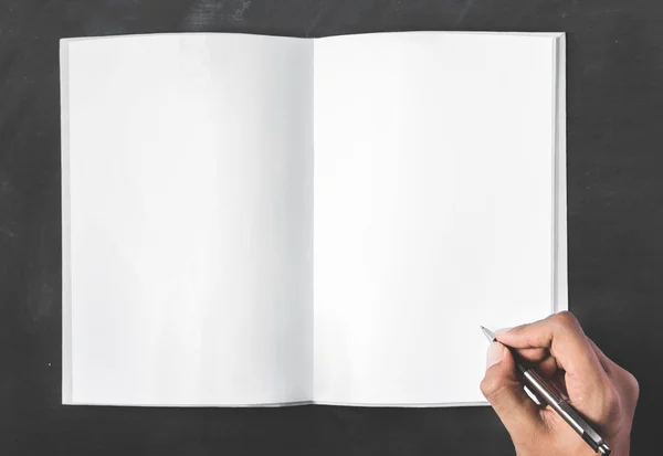 Open book with blank page and hands holding a pen — Stock Photo, Image