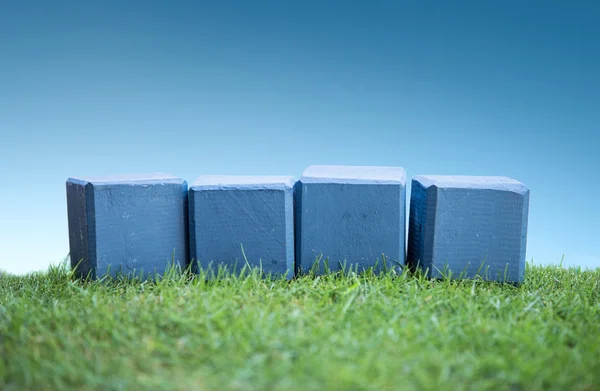 Wooden blocks on a green grass, plain white — Stock Photo, Image