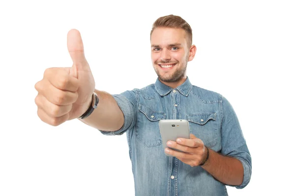 Ung man innehar en mobil, tummen upp — Stockfoto