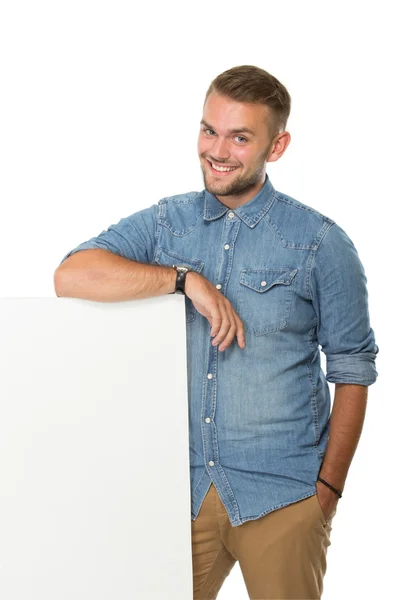 Mladý muž, stojící vedle prázdné bílé billboard — Stock fotografie