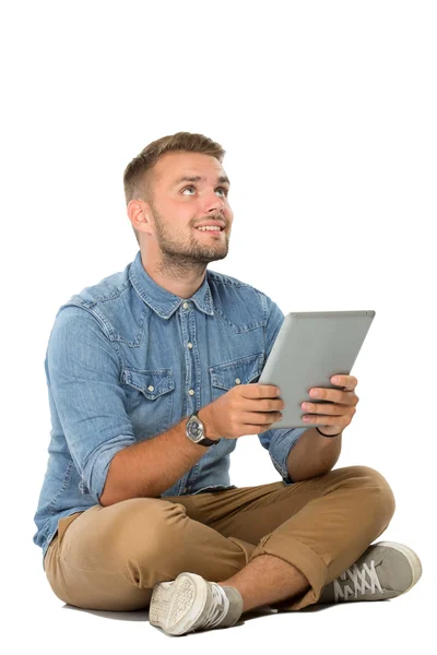 Młody człowiek siedzi na podłodze, wyobrażając sobie, trzymając smartpho — Zdjęcie stockowe