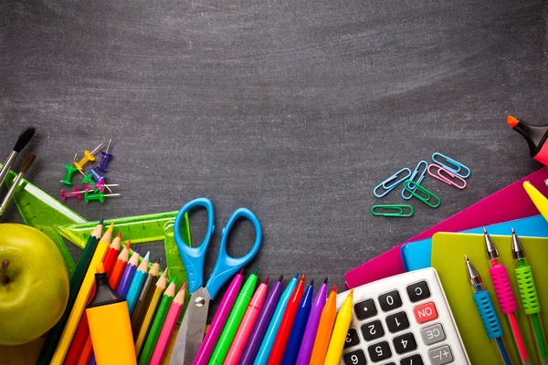 Colorful stationery on blackboard — Stock Photo, Image