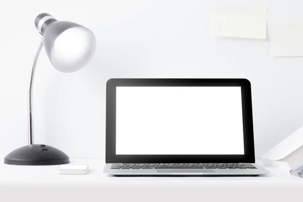 Laptop and reading lamp at desk with scrap paper on the wall — Stock Photo, Image