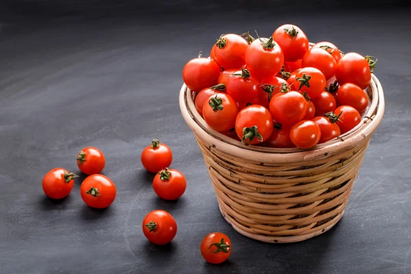 Hromadu cherry rajčat v proutěném koši — Stock fotografie