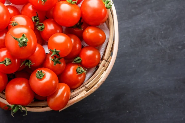 Pilha de tomates cereja em uma cesta de vime — Fotografia de Stock