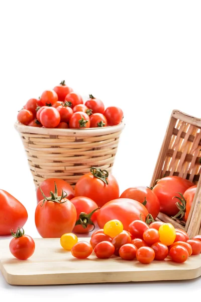 Varios tipos de tomates en la cesta de ratán y corte de madera bo —  Fotos de Stock