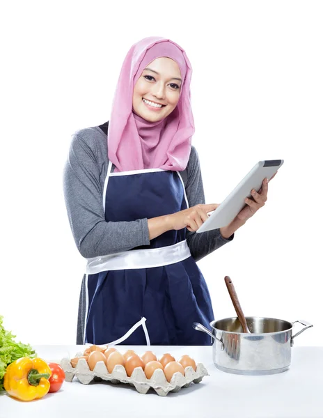 Beautiful young  woman reading cooking recipe on tablet while ma — Stockfoto