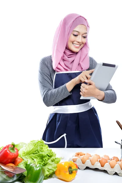 Hermosa mujer joven leyendo receta de cocina en la tableta mientras ma —  Fotos de Stock