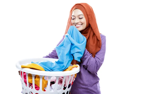 Young woman wearing hijab carrying laundry basket while smelling — Stock Photo, Image