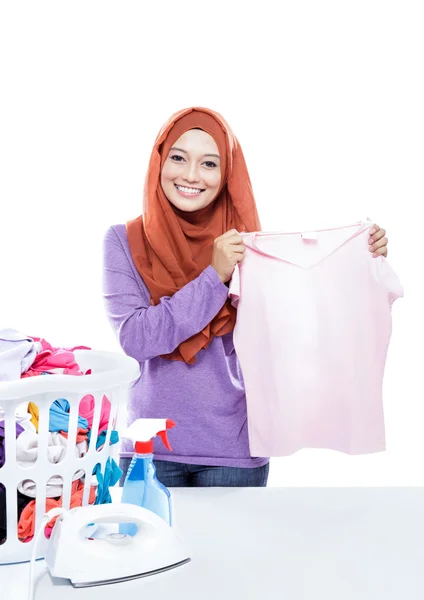 Junge Frau bügelt Hijab, während sie Kleidung aufnimmt — Stockfoto